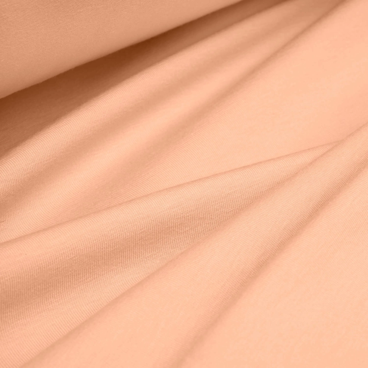 Draped peach jersey fabric – lightweight, elastic material ideal for clothing and handmade use.