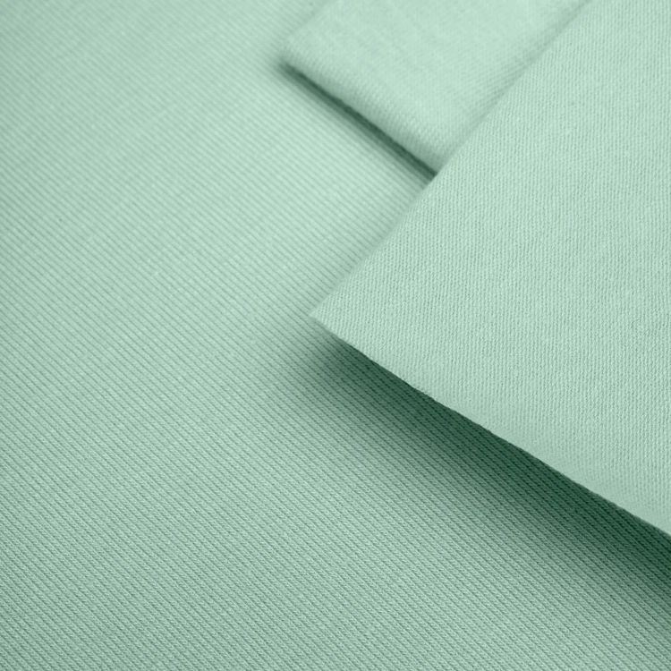 Close-up view of soft mint green cotton jersey fabric with folded layers